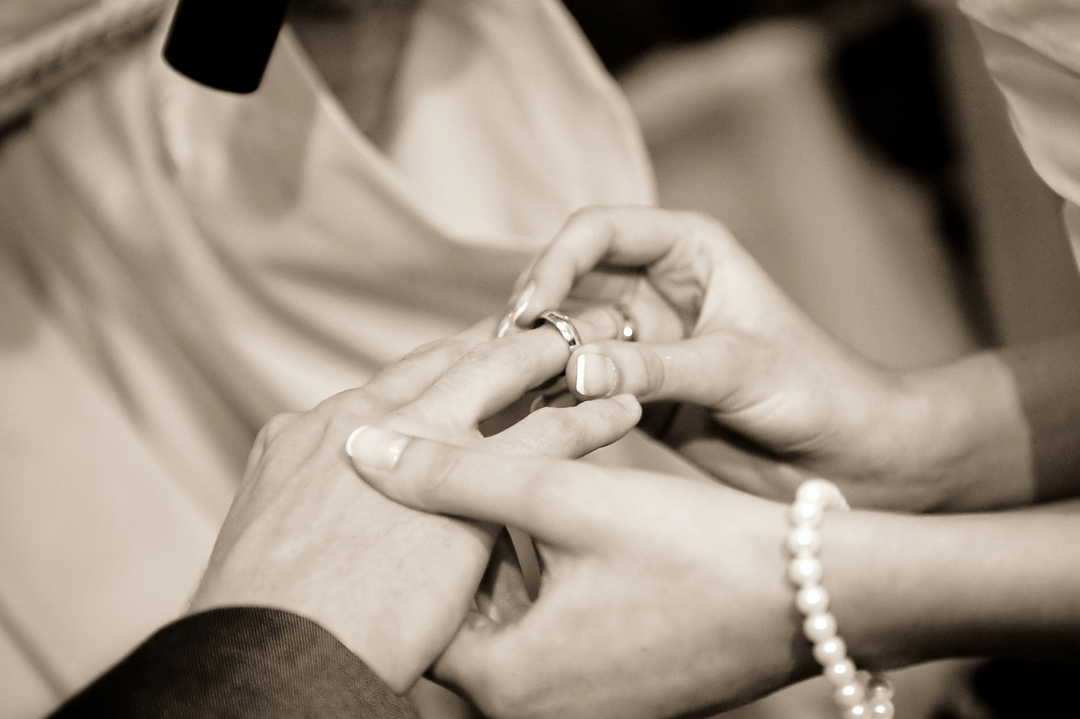 Close-up of a wedding ring being placed on a bride’s finger during a ceremony.